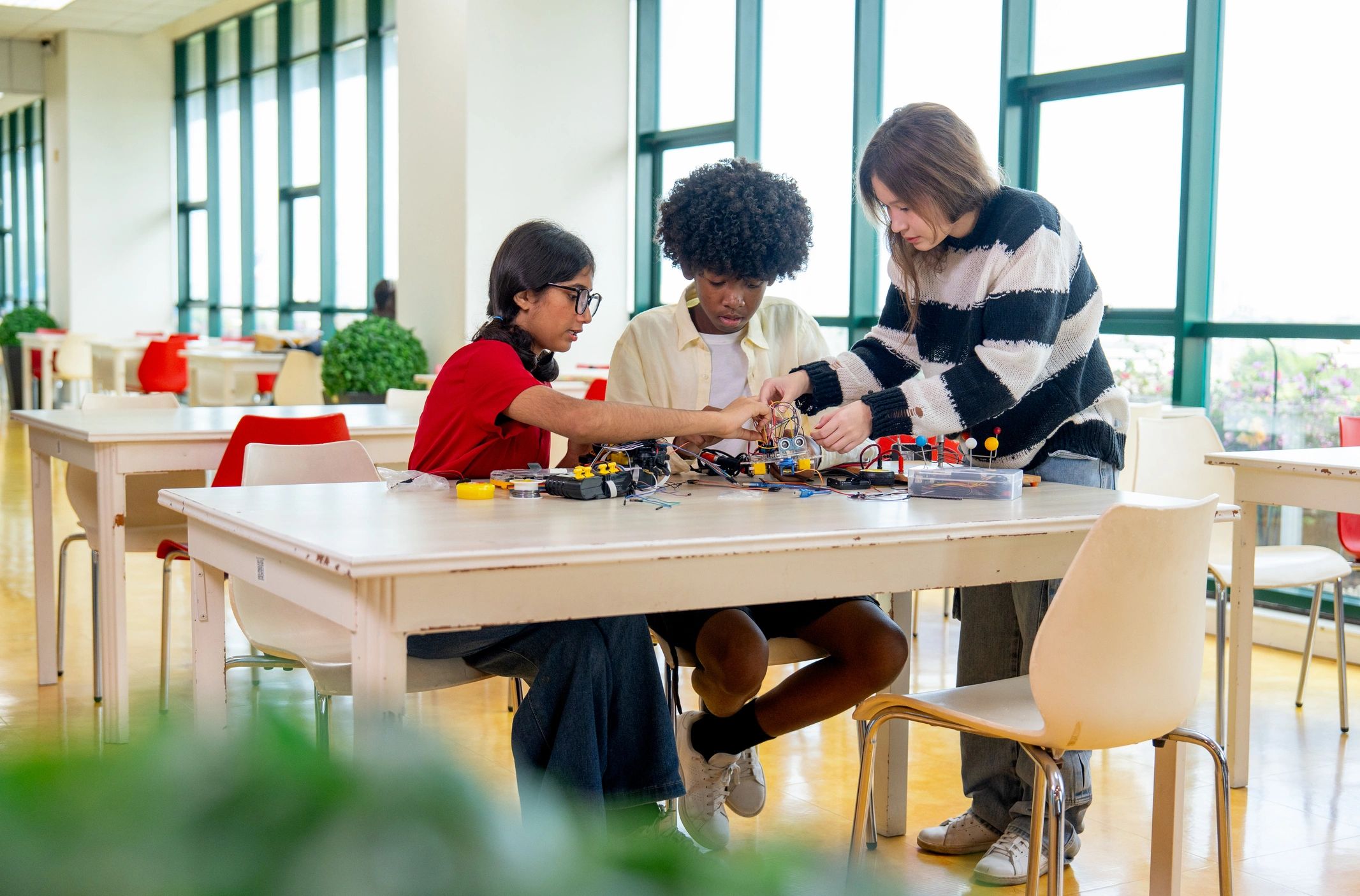 Teenagers assembling a robot together in a library setting