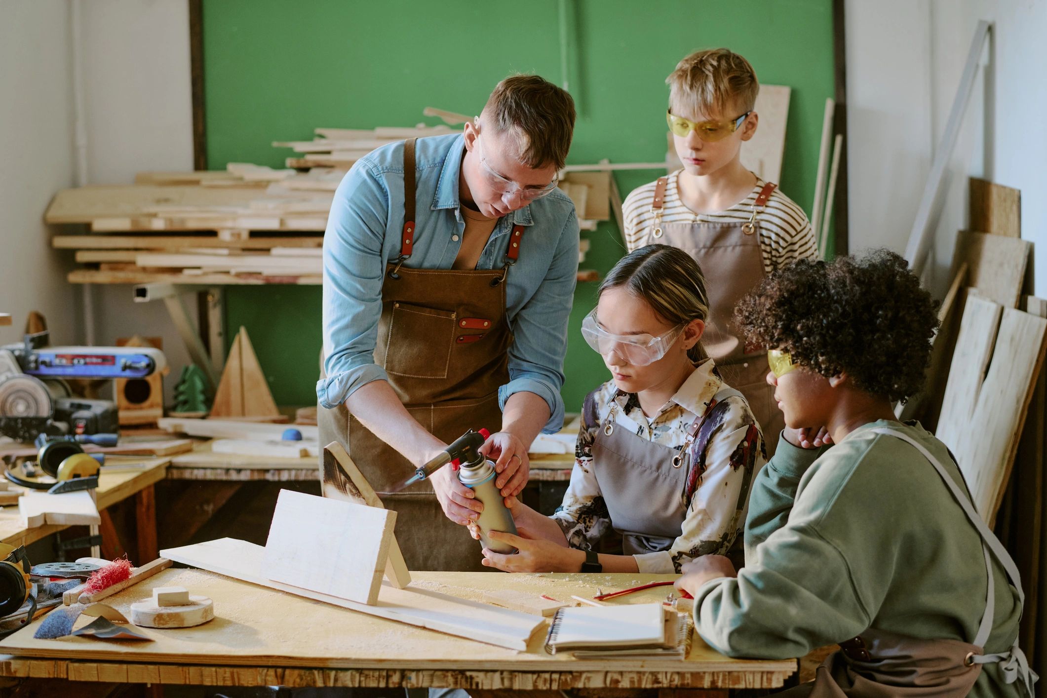 Teenagers learning practical workshop skills with an instructor