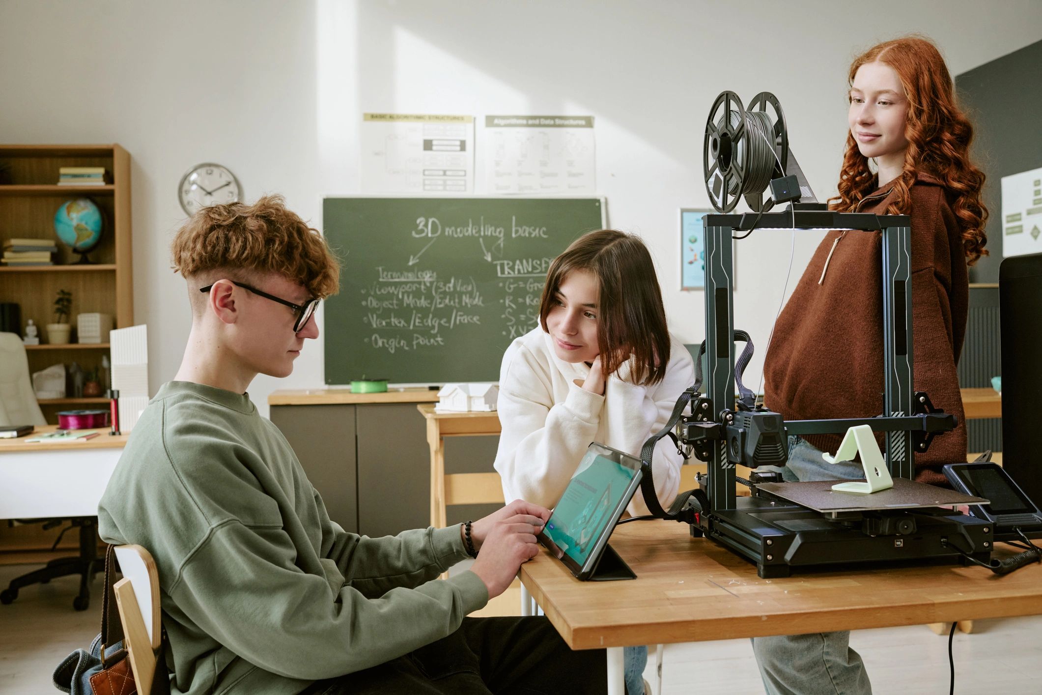 Teenagers using a 3D printer and tablet